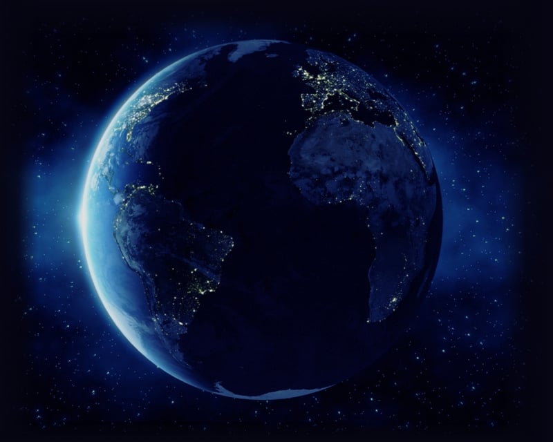 Earth floating in space with small sliver lit and rest in shadow